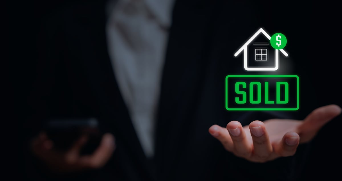 Real estate success — professional holding a sold home icon representing a completed cash deal